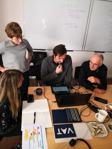 Softwareentwickler und Kunden sitzen an einem Tisch und diskutieren